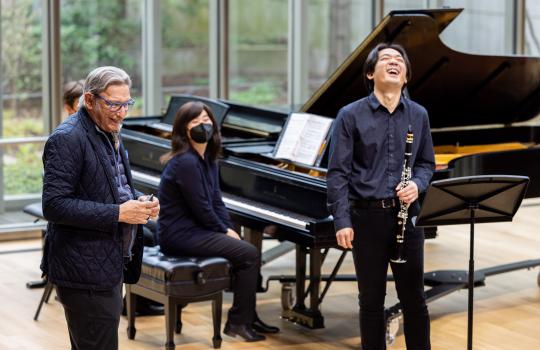 Michael Tilson Thomas laughs with a student on stage in Mixon Hall. 