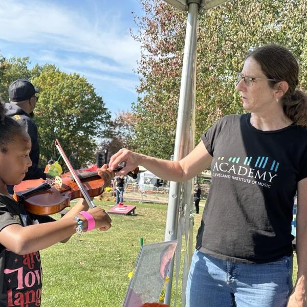 Someone from the Cleveland Institute of Music works with a child at Parade the Circle.
