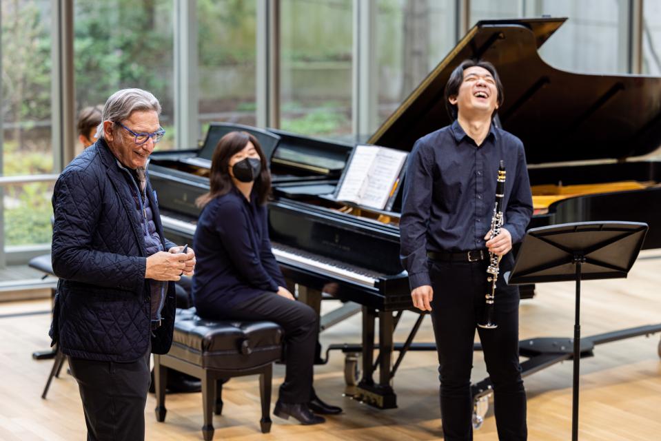 Michael Tilson Thomas laughs with a student on stage in Mixon Hall. 