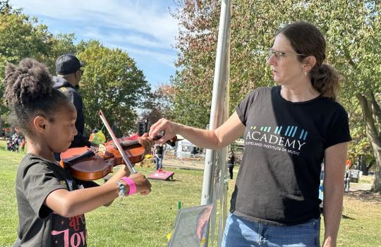 Someone from the Cleveland Institute of Music works with a child at Parade the Circle.