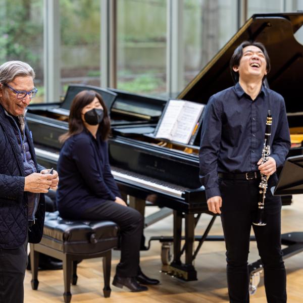 Michael Tilson Thomas laughs with a student on stage in Mixon Hall. 