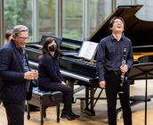 Michael Tilson Thomas laughs with a student on stage in Mixon Hall. 